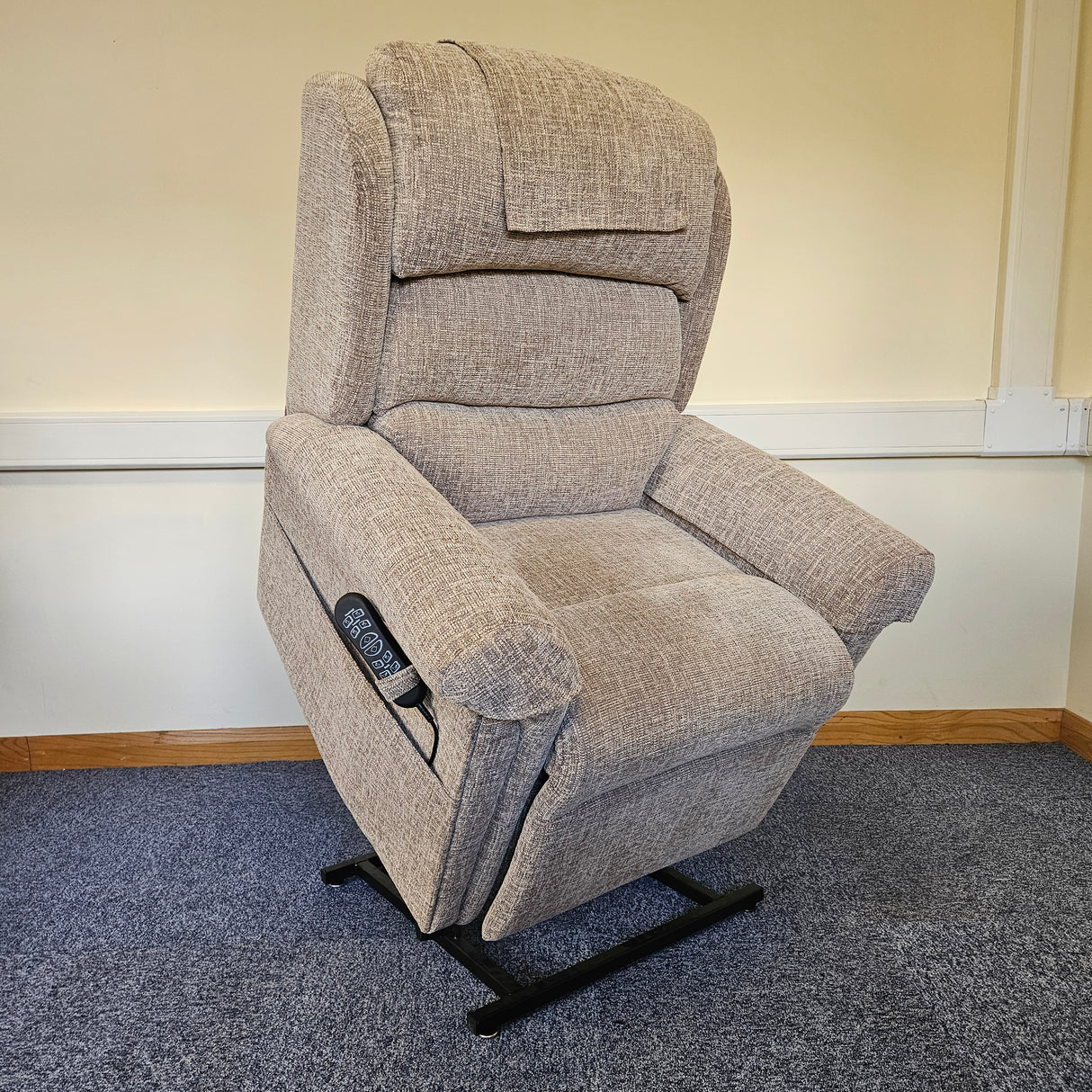 Gray recliner chair with remote control on a carpeted floor.