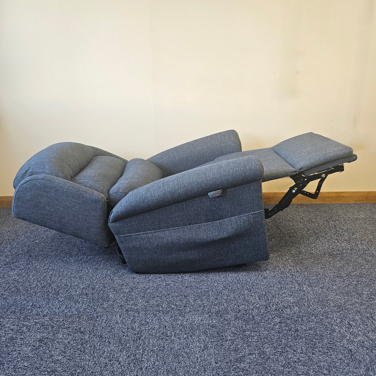 Blue recliner sofa on a carpeted floor with a plain wall background