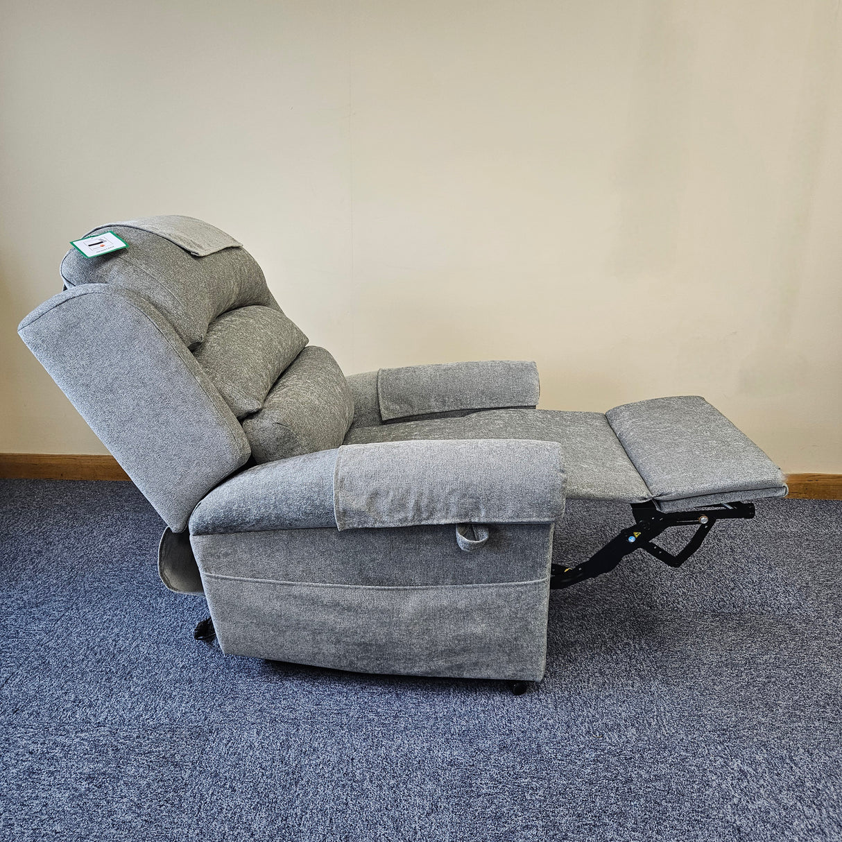 Gray recliner chair on a blue carpet with a beige wall background