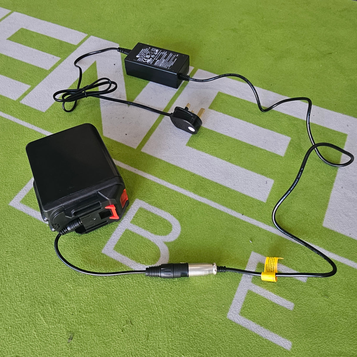 Battery charger and battery on a green surface with text