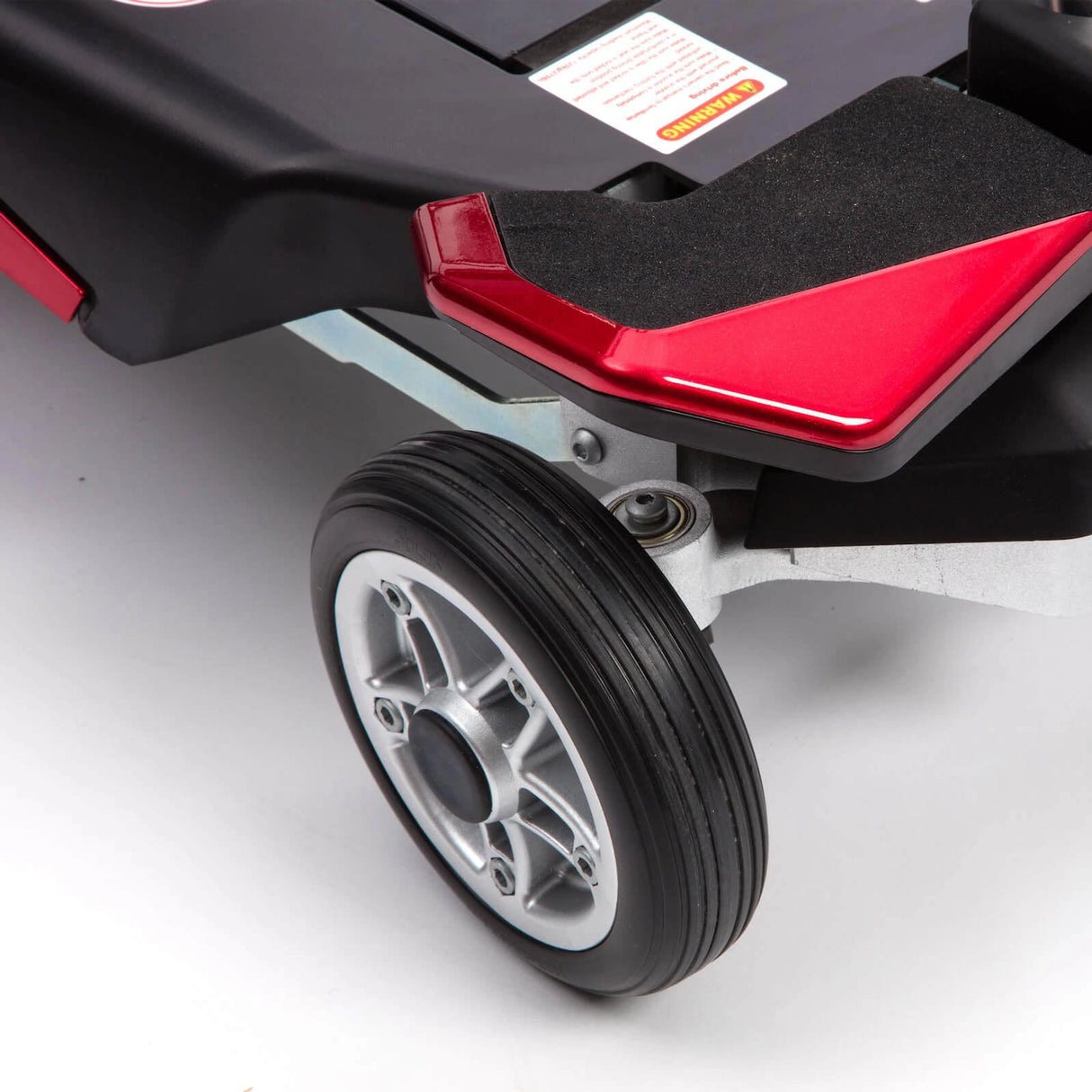 Close-up of a wheel and red footrest on a mobility scooter.