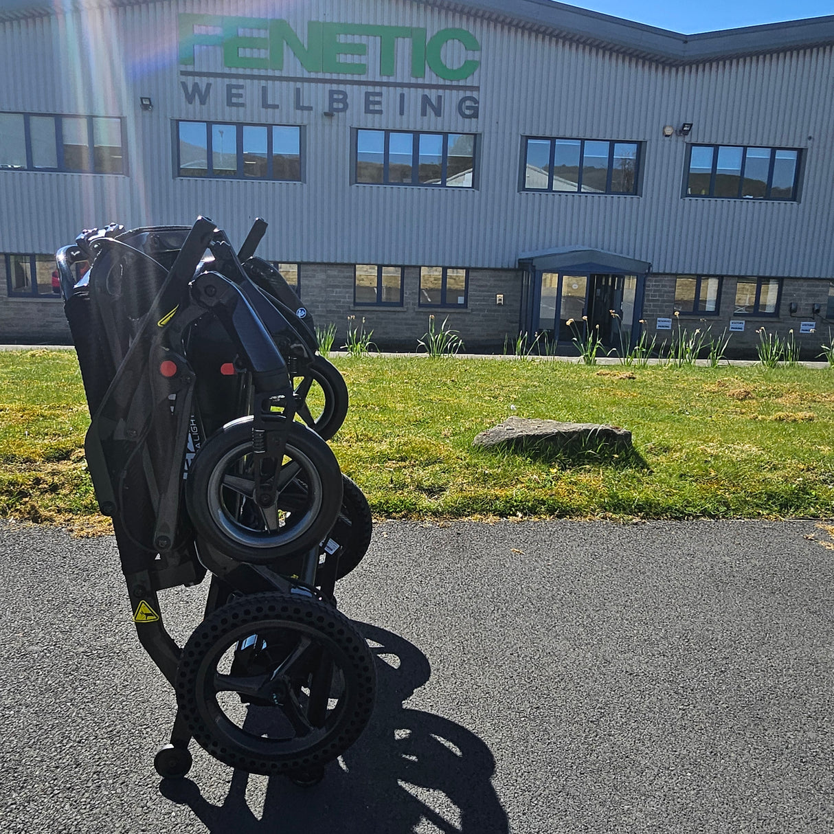 Black scooter in front of a building with 'Fenetic Wellbeing' branding.