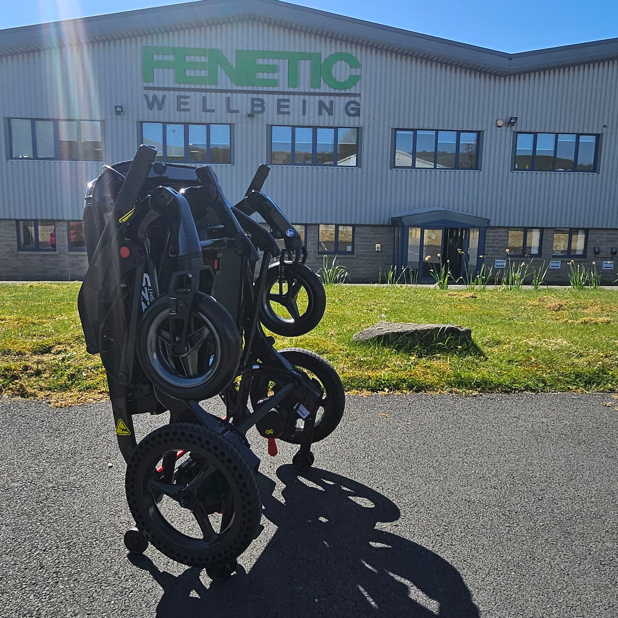 Folded electric wheelchair on a driveway with a building in the background