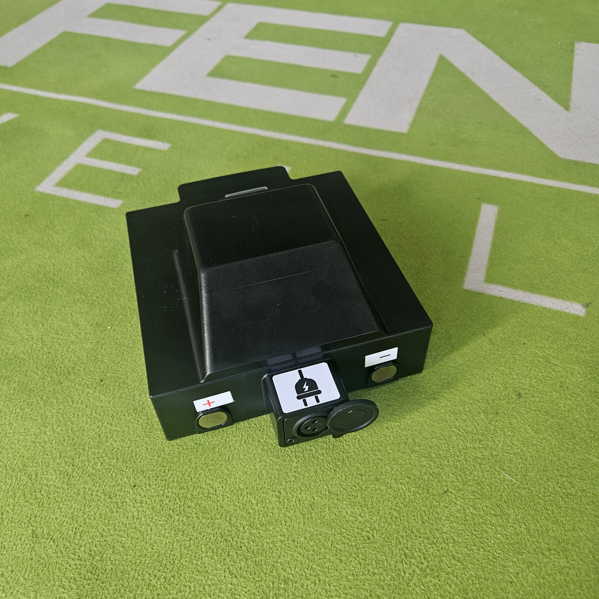 Black electrical component on a green surface with text