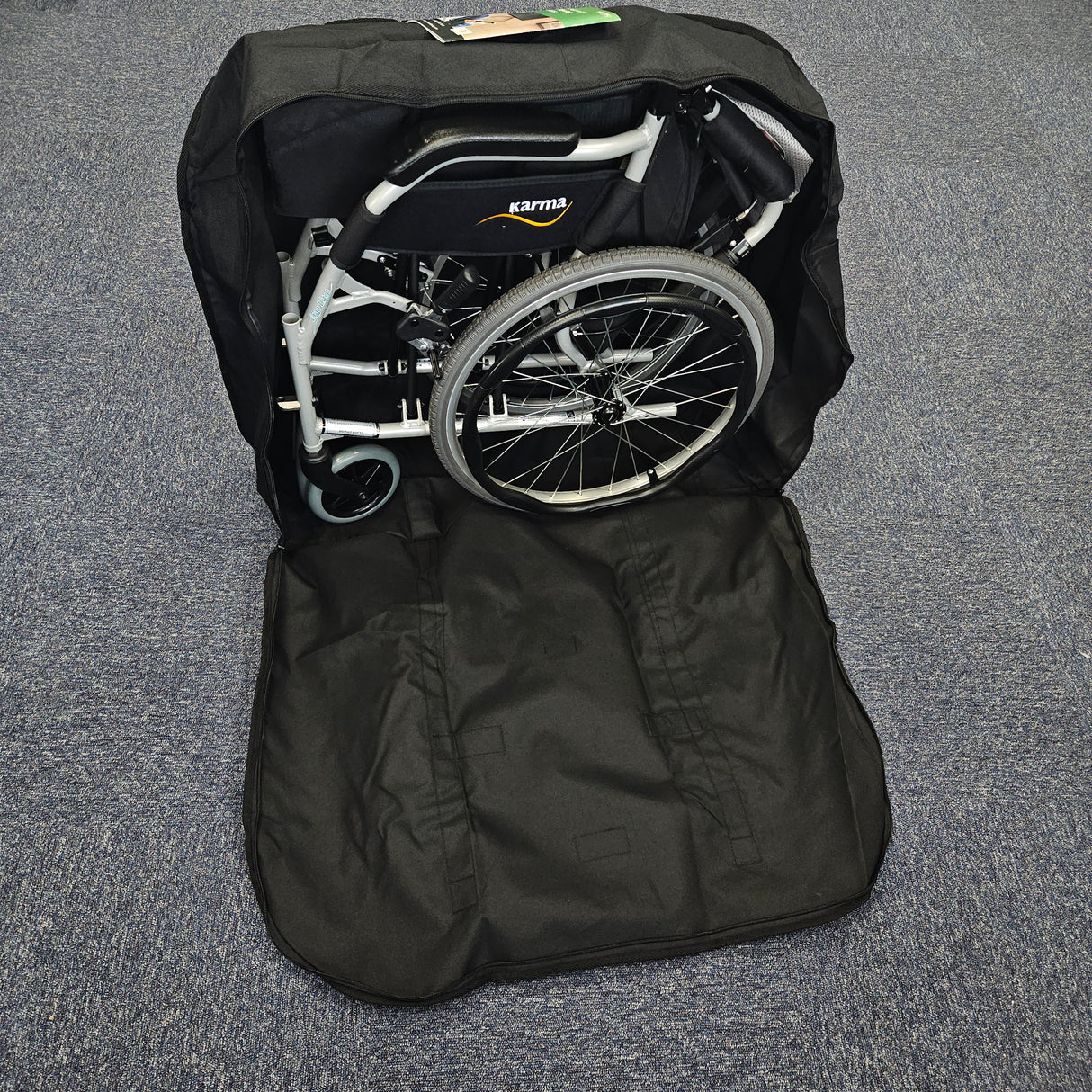 Foldable wheelchair inside a black carrying bag on a gray floor.