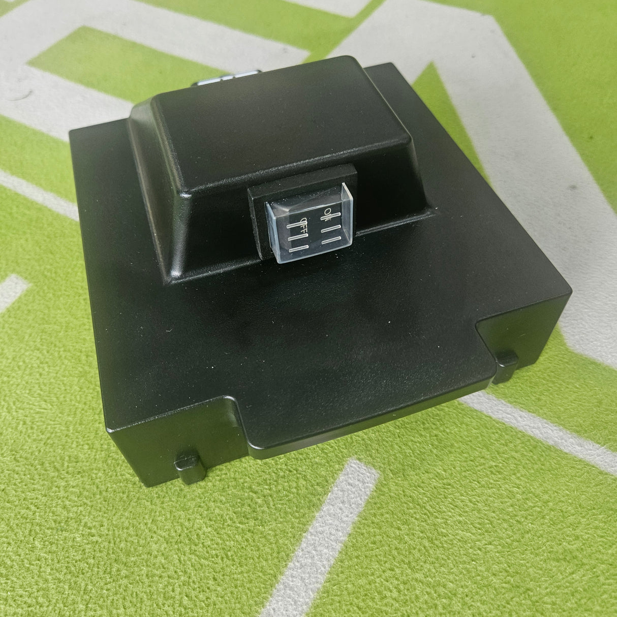 Black rectangular battery on a green surface