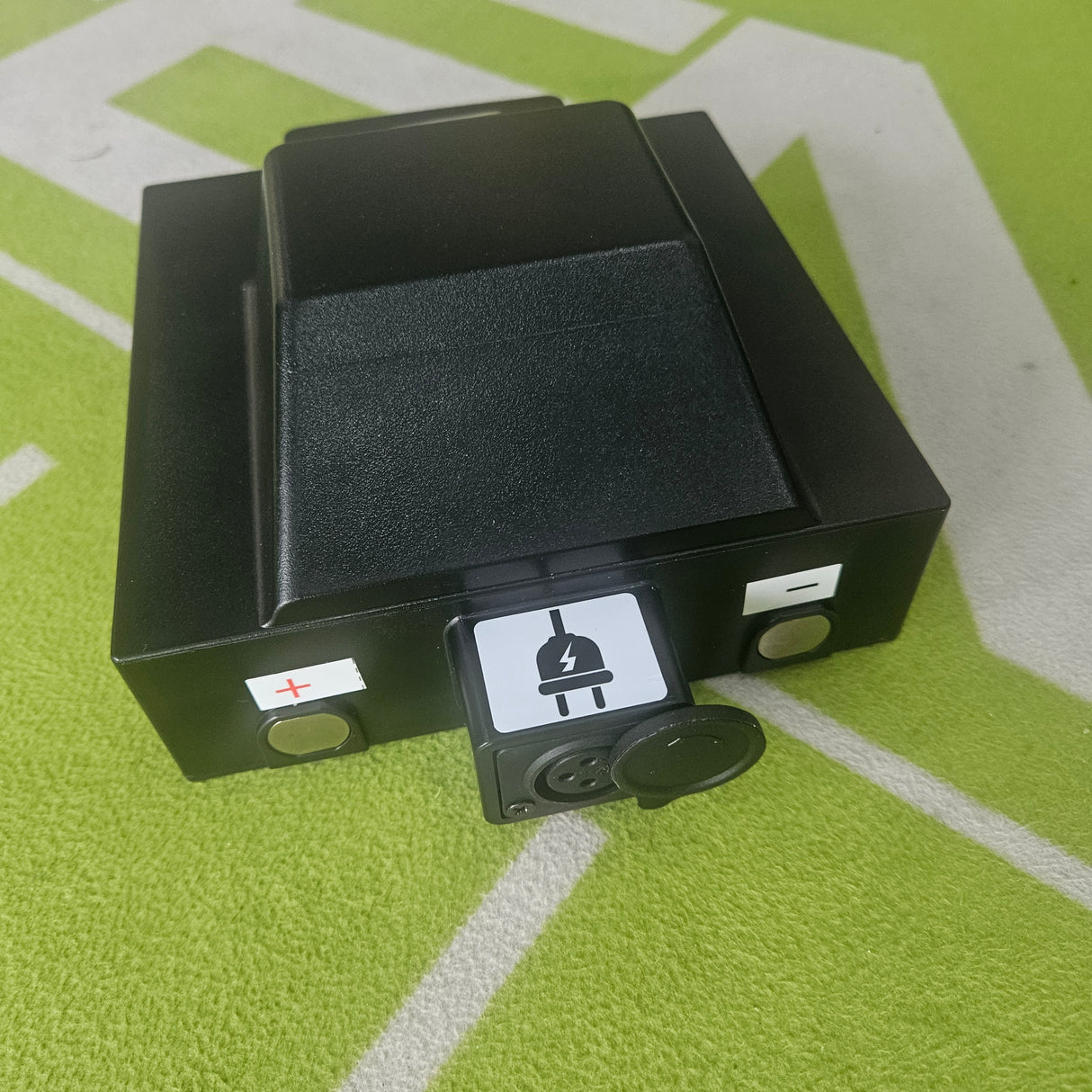 Black battery on a green surface