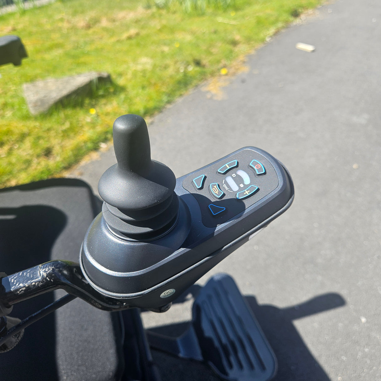 Close-up of a powerchair with control buttons on a blurred outdoor background