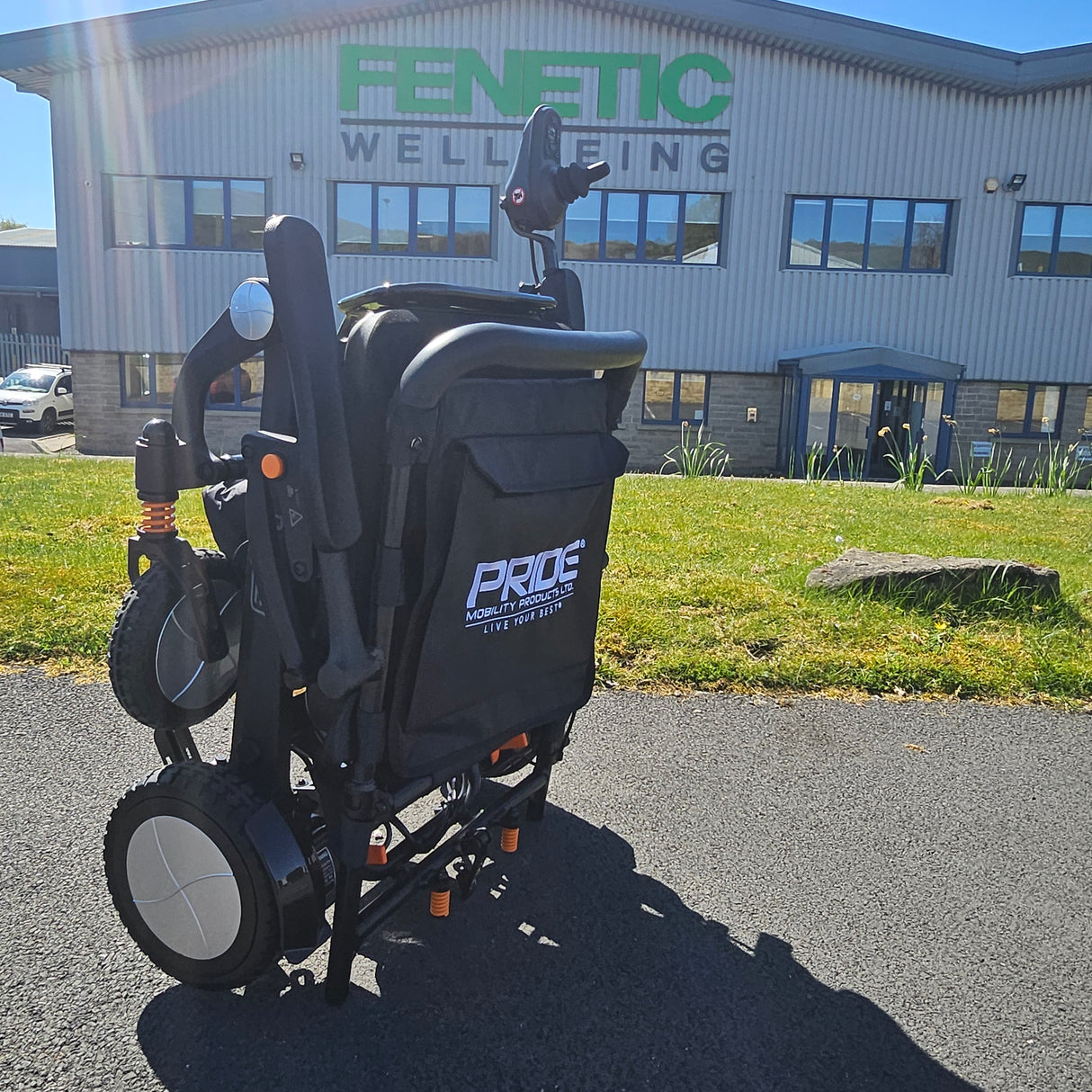 Electric wheelchair with Pride logo in front of a building with 'Fentic Wellbeing' branding.