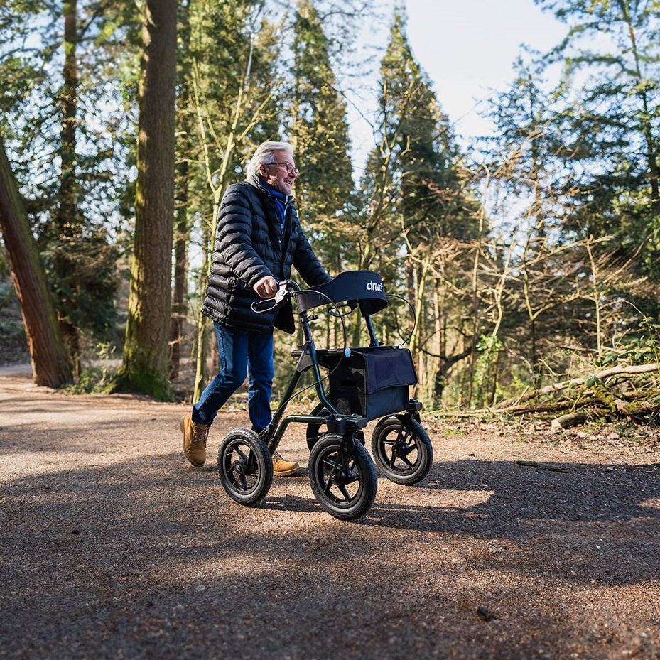 Man pushing a rollator through a forest path