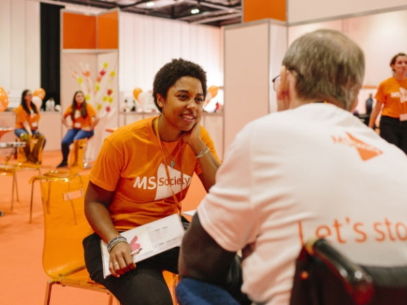 MS Society volunteer supporting a participant at a community wellbeing event, illustrating the kind of initiatives supported by Fenetic Wellbeing through its contributions to multiple sclerosis care.