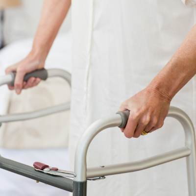 Home aids for your parents, showing an older person using a supportive walking frame to improve stability and mobility at home.