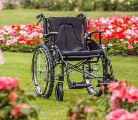 All terrain wheelchair positioned on grass in a vibrant spring garden with colourful flowers, highlighting outdoor accessibility and mobility.
