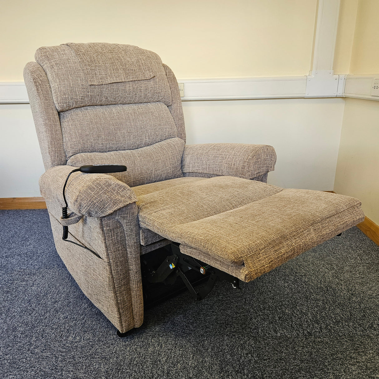 Gray recliner chair in a room with carpeted floor and white walls.