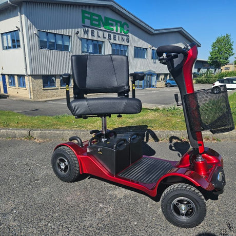 Red mobility scooter parked in front of a building with 'Fenetic Wellbeing' signage.