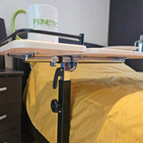 Bed with a yellow blanket and a mug on a mobility table in a room.