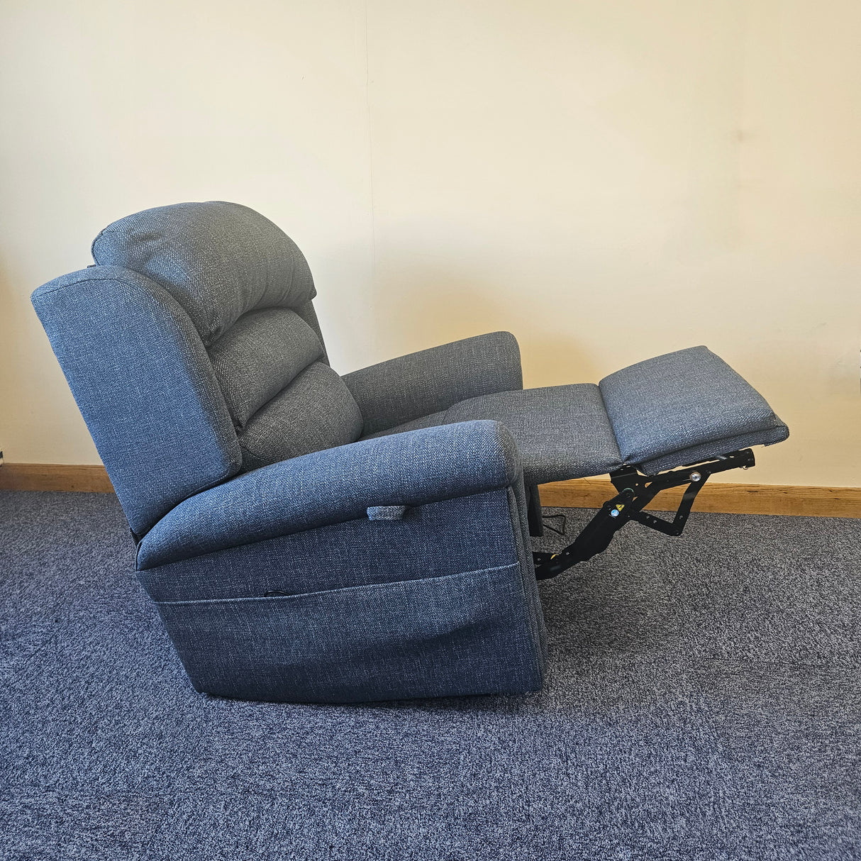 Blue recliner chair on a carpeted floor with a plain wall background
