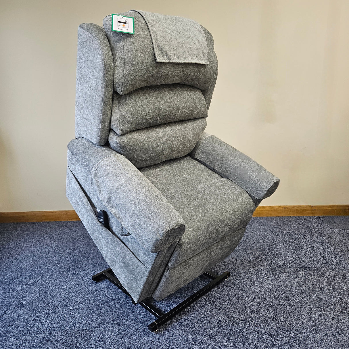 Gray recliner chair on a blue carpet with a beige wall background