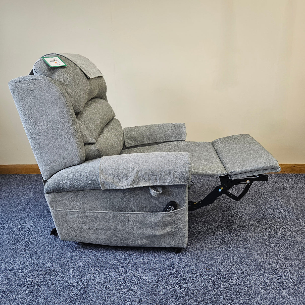 Gray recliner chair on a blue carpet with a beige wall background
