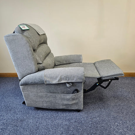 Gray recliner chair on a blue carpet with a beige wall background