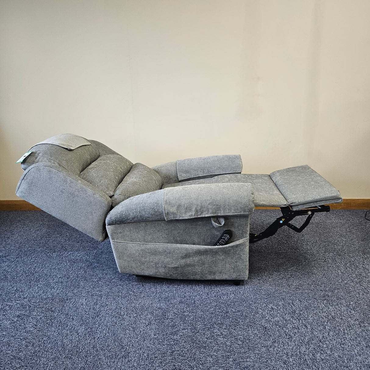 Gray recliner chair on a blue carpeted floor with a beige wall background
