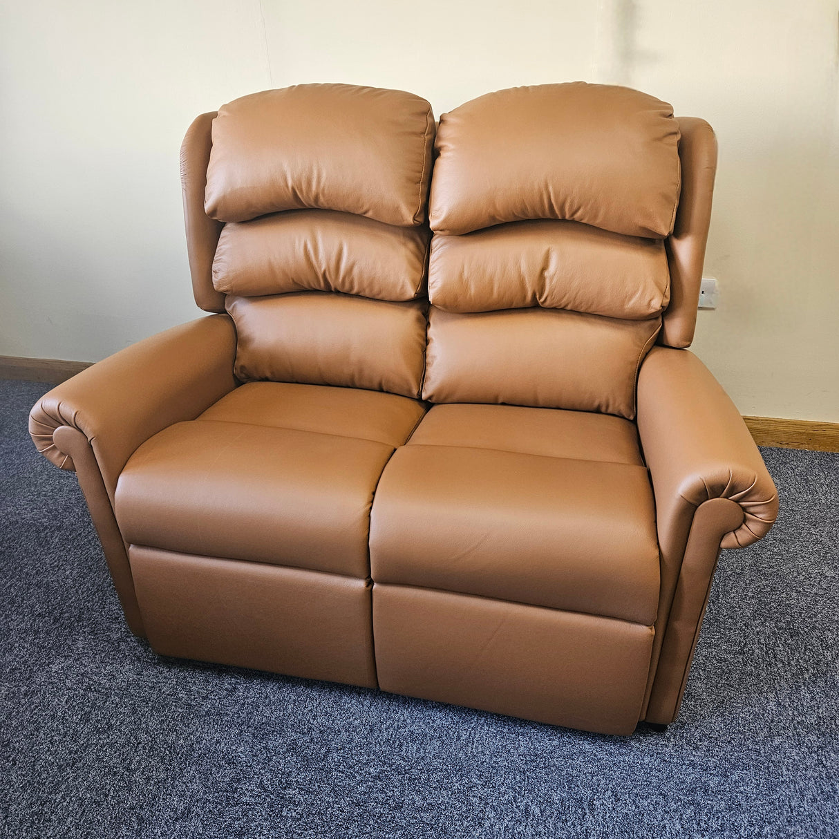 Brown leather sofa on a blue carpet with a white wall background