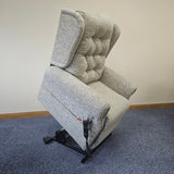 Gray upholstered chair against a white wall with a blue carpeted floor.
