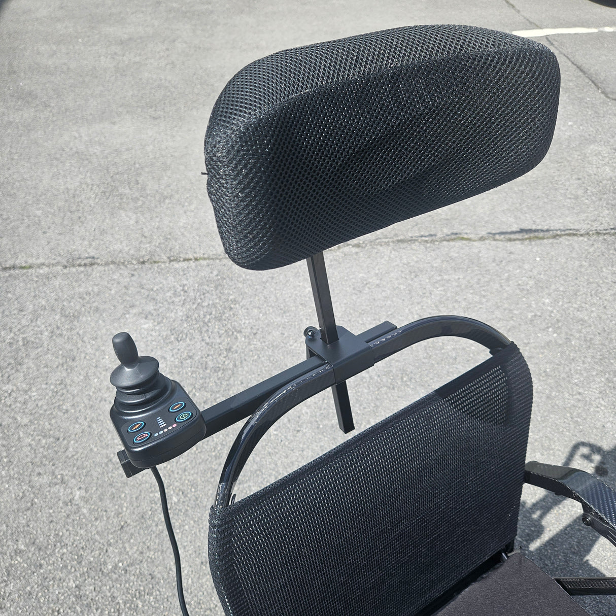 Black mesh chair with control panel on a concrete surface