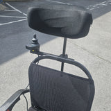 Black power chair with mesh backrest on a concrete surface