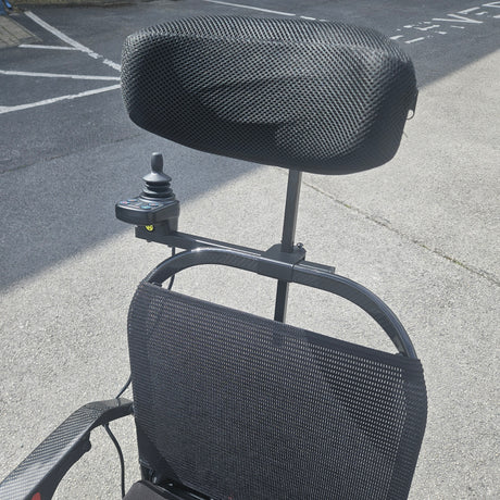 Black power chair with mesh backrest on a concrete surface
