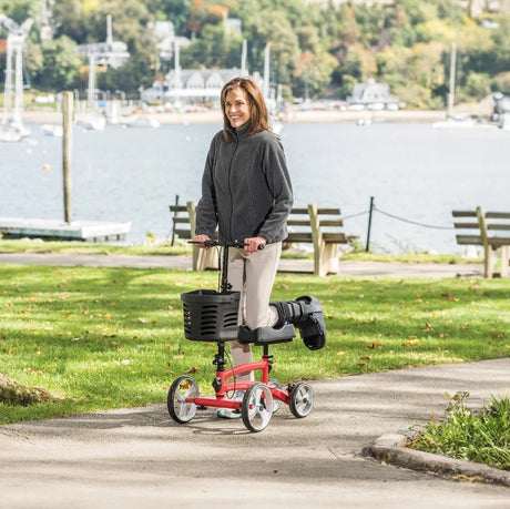 Person using a knee scooter on a path by a waterfront