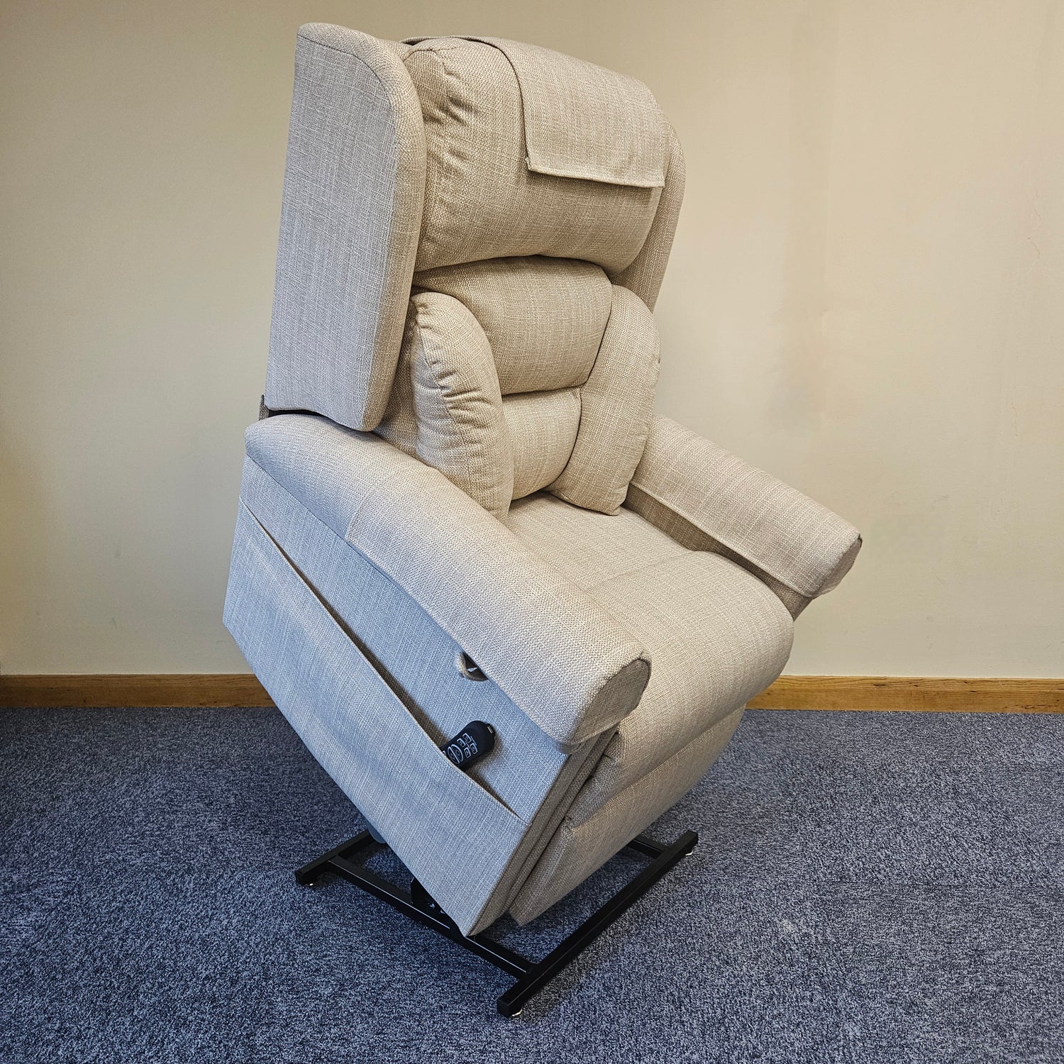 Beige recliner chair on a blue carpeted floor with a plain wall background