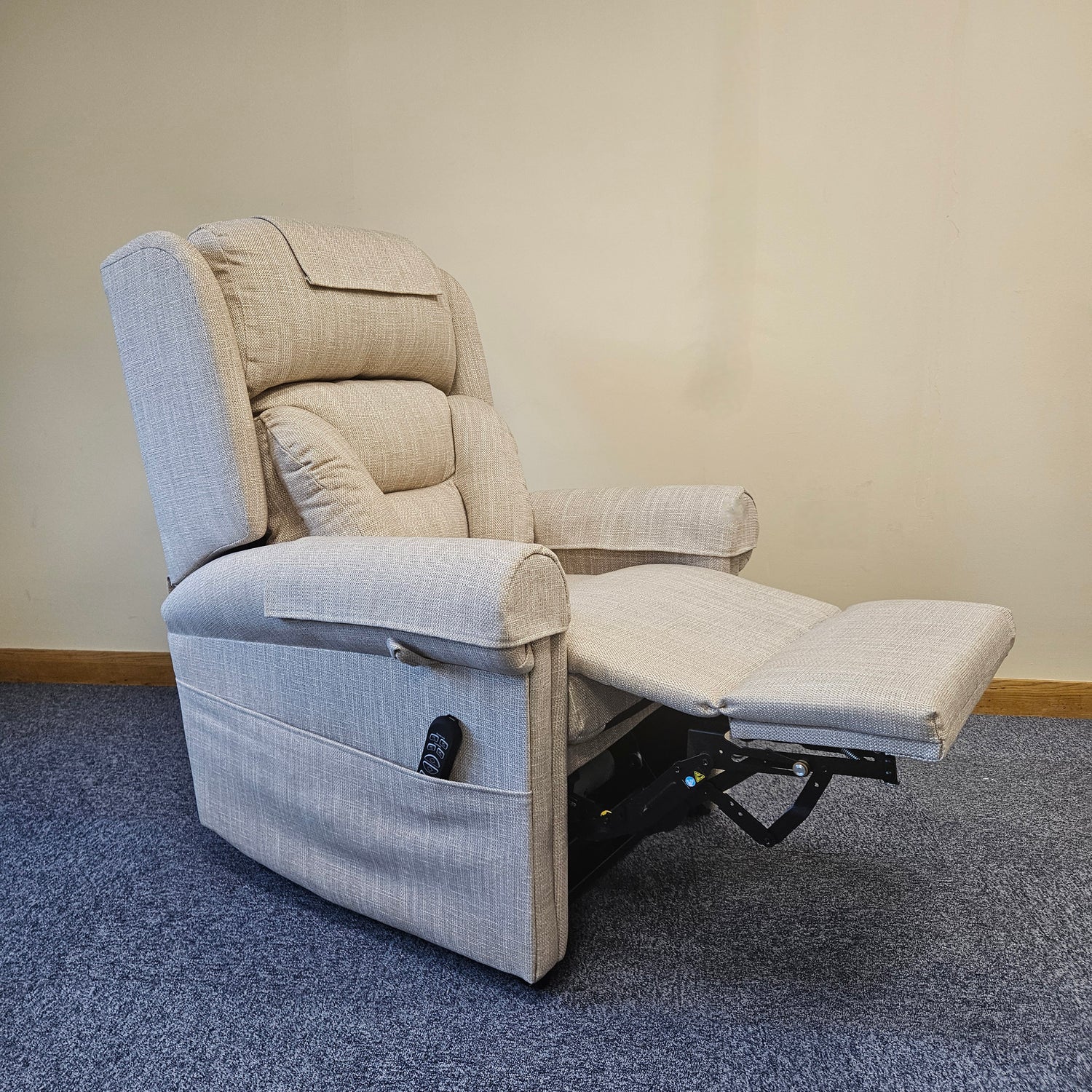 Gray recliner chair with armrests and footrest on a carpeted floor.