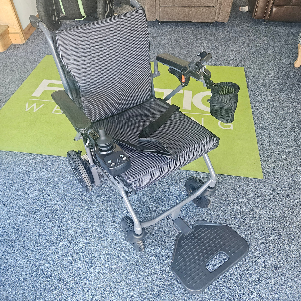 Power wheelchair on a carpeted floor with a green mat underneath