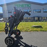 Folded powerchair on a driveway with a building in the background