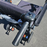 Close-up of a power chair's handlebar and control panel on a gray pavement.