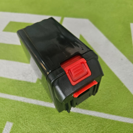 Black and red battery pack on a green surface