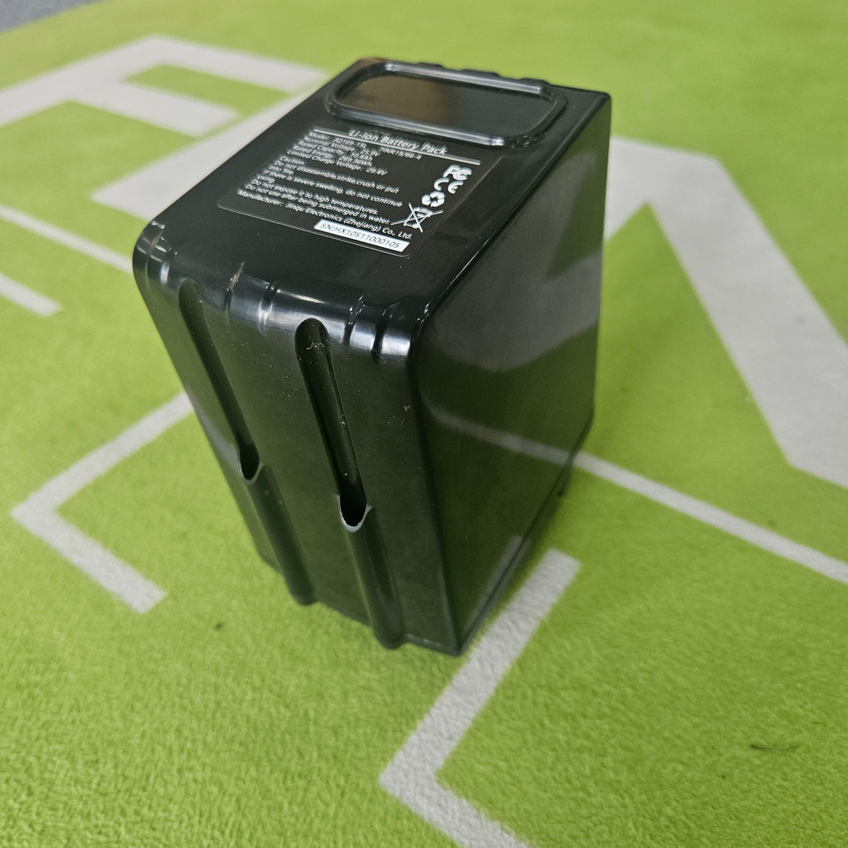 Black battery pack on a green surface