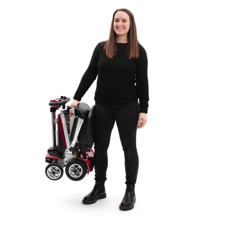 Person holding a folded mobility scooter on a white background