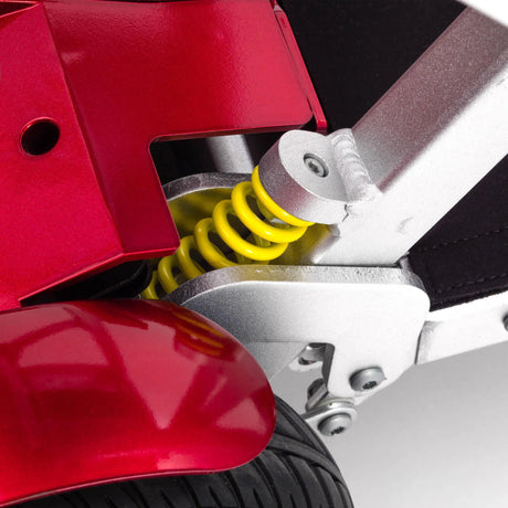 Close-up of a mobility scooter suspension system with red and silver components.