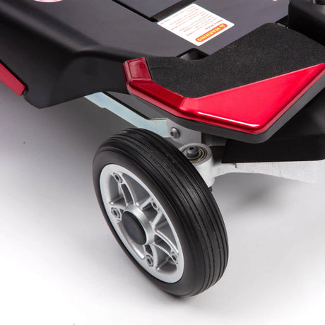 Close-up of a wheel and red footrest on a mobility scooter.