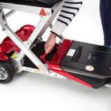 Red and black scooter with a person's hand on a white background