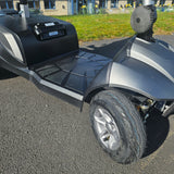 Close-up of a scooter's wheel and front section on an outdoor surface.