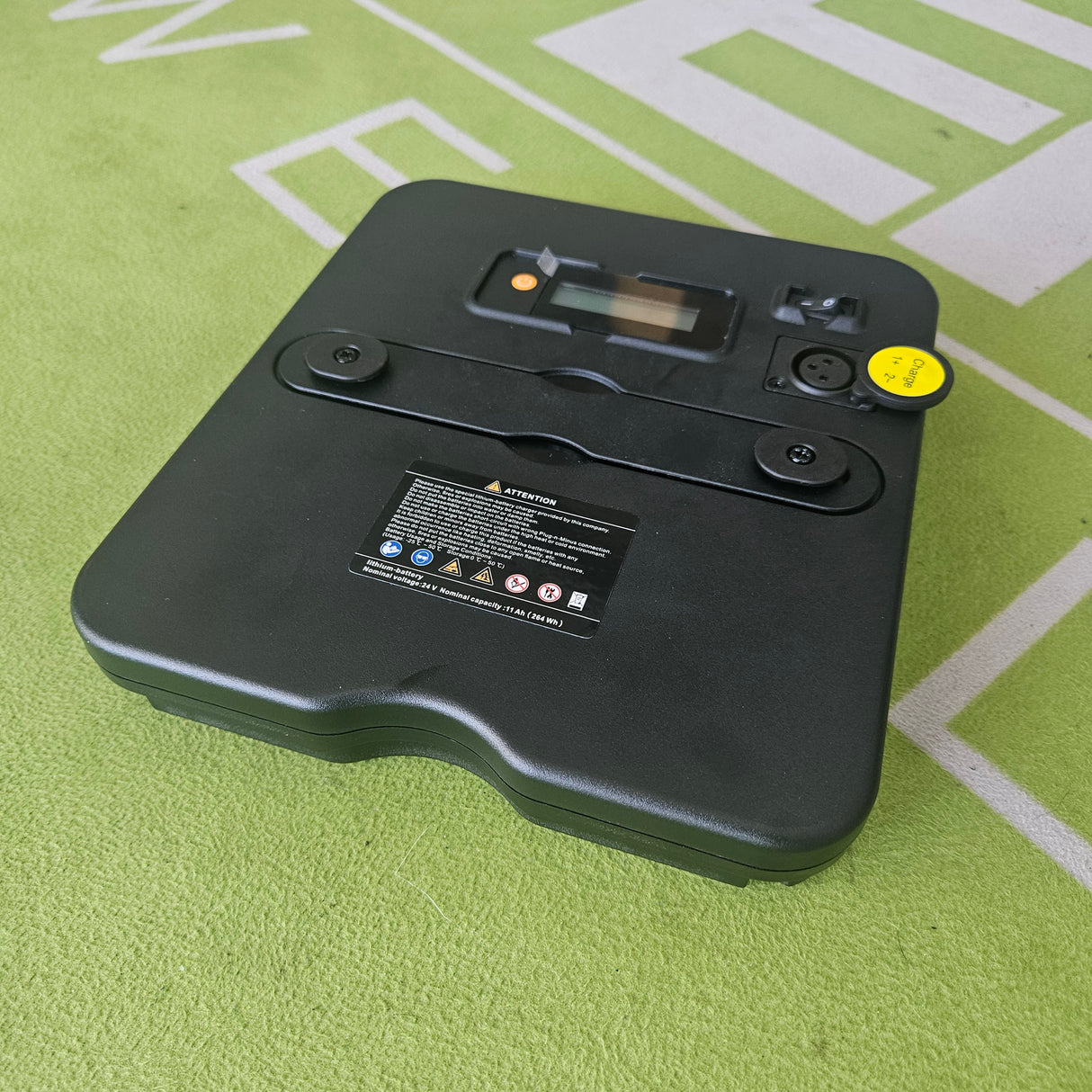 Black electronic device with a yellow sticker on a green surface