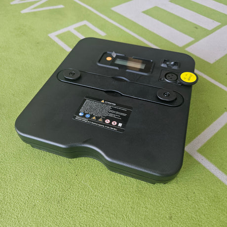 Black electronic device with a yellow sticker on a green surface