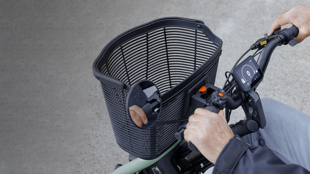 Person using a scooter with a basket attached on a gray background