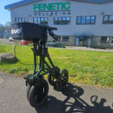 Foldable rollator on a grassy area with a building in the background