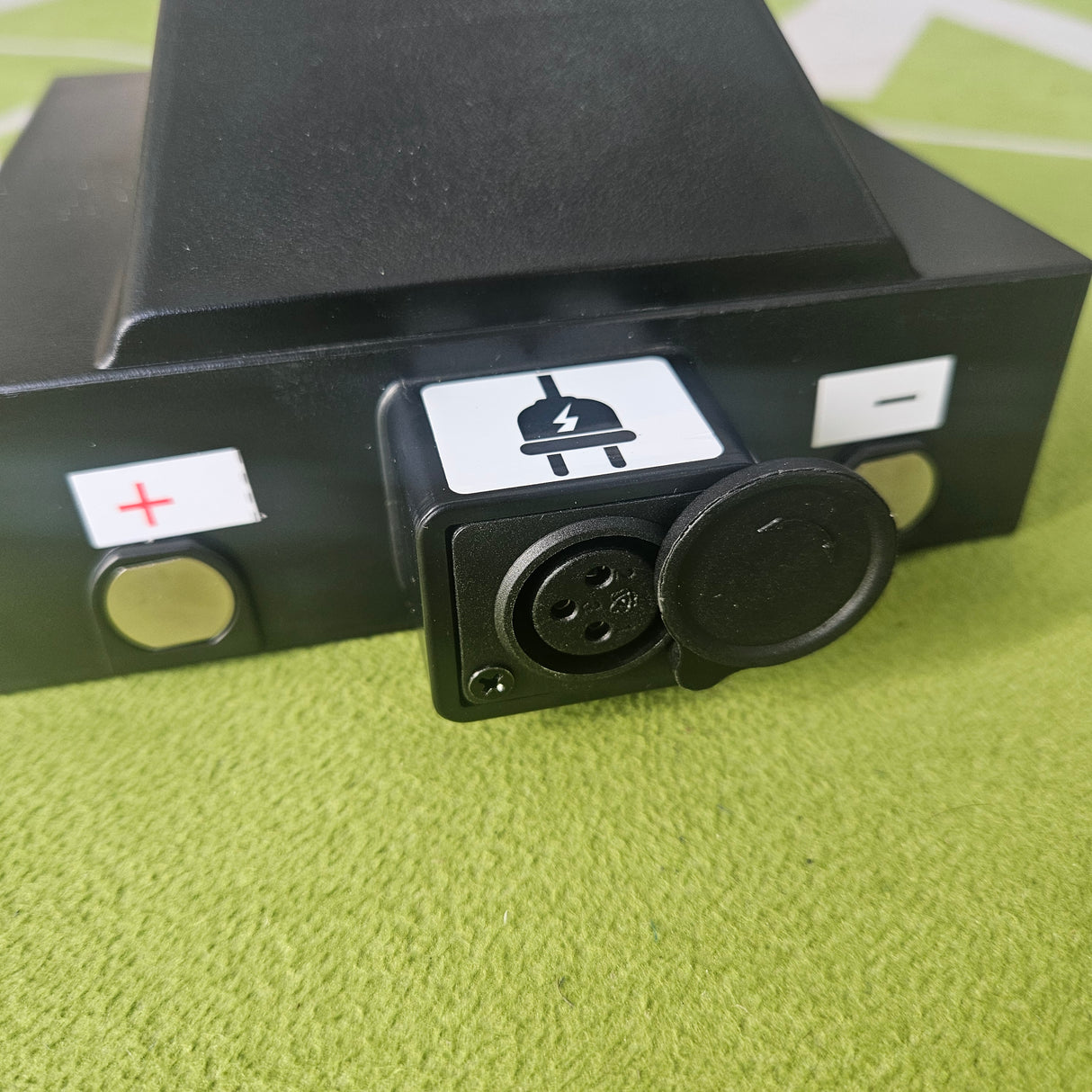 Black electronic component with connectors on a green textured surface