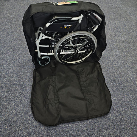 Foldable wheelchair inside a black carrying bag on a gray floor.