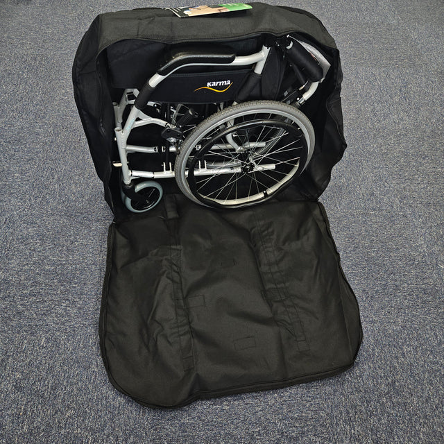 Foldable wheelchair inside a black carrying bag on a gray floor.